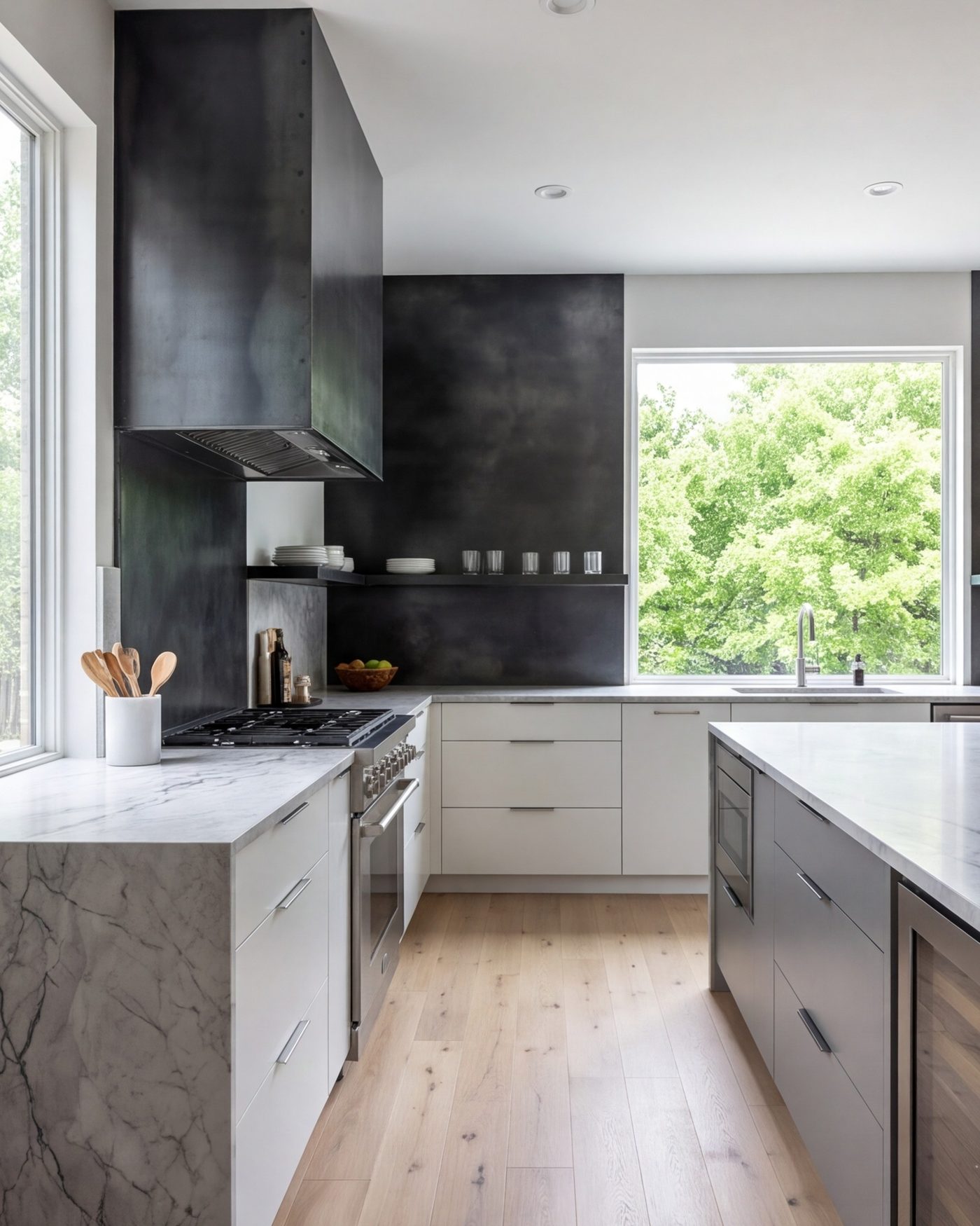 tall view of a cool finished kitchen, grey-veined stone, blackened steel range wall, pale oak floor
